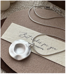 Macro view of S925 sterling silver necklace showing matte irregular pendant and snake chain