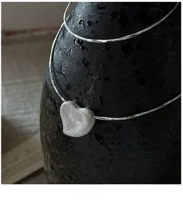 Macro detail of S925 sterling silver heart necklace with brushed matte metal finish