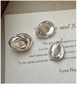 Macro detail of silver S925 drop earrings with matte finish and organic pebble shape