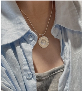 Detailed view of matte silver pendant with irregular hammered texture on snake chain