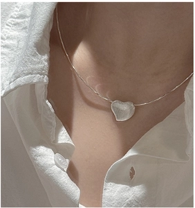 Close-up of S925 sterling silver heart necklace with brushed texture on model