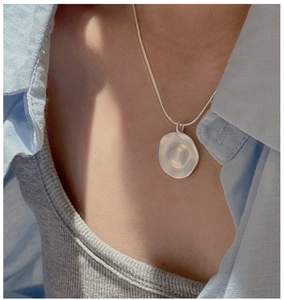 Close-up of matte S925 silver necklace with irregular wrinkled pendant on model