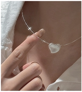 Detail of S925 silver heart choker with matte white pendant on model's neckline