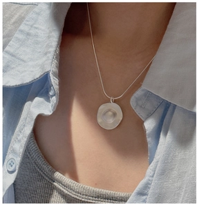 Macro shot of matte silver irregular organic pendant on a fine snake chain necklace