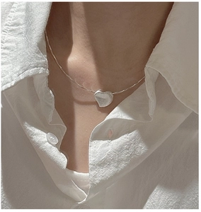 Close-up of S925 sterling silver heart necklace with a brushed finish on model neck
