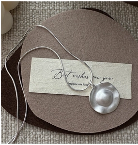 Close-up of matte S925 silver irregular disc pendant on a sleek snake chain necklace