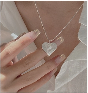 Gros plan du pendentif cœur en argent S925 avec texture martelée sur une chaîne à billes