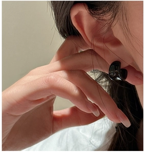 Vista macro di orecchini a cerchio minimalisti in smalto nero lucido indossati sulla modella
