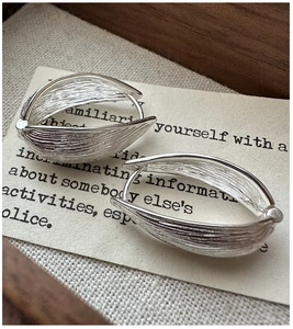 Macro view of vintage silver earrings featuring detailed vertical brushed texture and oval shape