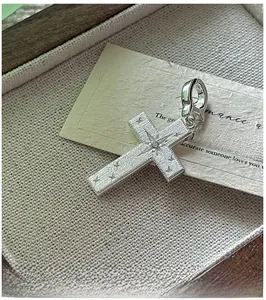 Close-up of S925 sterling silver cross pendant with brushed texture and star engraving