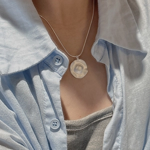 Minimalist S925 silver irregular wavy pendant necklace worn with a light blue linen shirt