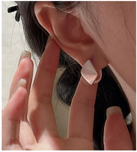 Close-up of minimalist S925 sterling silver rhombic earrings with brushed metal texture