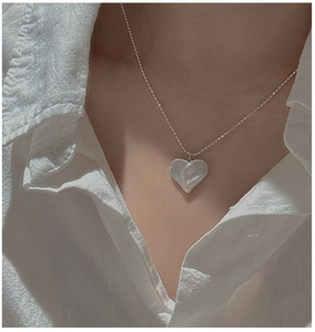 Détail du collier cœur en argent S925 avec texture brossée sur chemise blanche