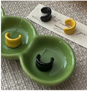 Dettaglio di orecchini a cerchio C spessi in smalto nero e giallo su ceramica