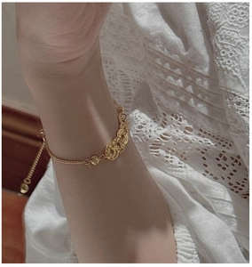Makroaufnahme des S925 Silberarmbands mit Goldmünzen am Handgelenk eines Models
