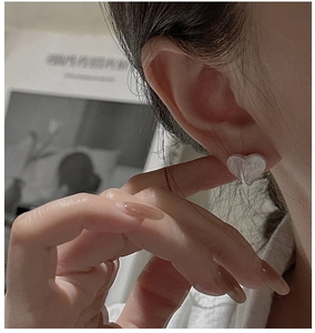 Close-up of minimalist S925 silver heart stud earrings with a brushed matte texture