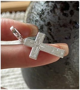 Detail of S925 sterling silver cross pendant with brushed finish and star engraving