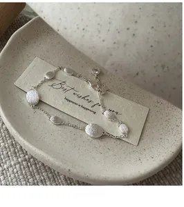 Macro detail of S925 sterling silver bracelet showing brushed oval beads and lobster clasp
