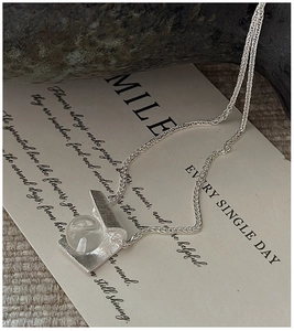 Close-up of S925 silver necklace with brushed metal pendant and white crystal sphere