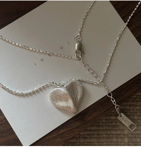 Détail macro du pendentif coeur en argent S925 avec texture brossée et étiquette Ag925
