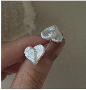 Macro shot of S925 sterling silver heart earrings with a brushed matte metal finish