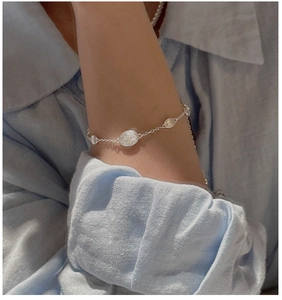 Detail of S925 sterling silver chain bracelet with oval textured charms on a female wrist