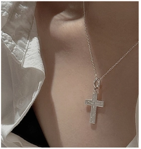 Macro view of brushed S925 sterling silver cross pendant with star engraving on neck