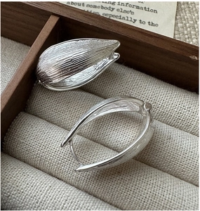 Close-up of S925 sterling silver hoop earrings with textured seed design and brushed finish
