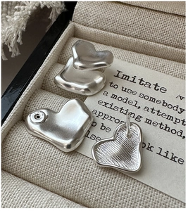 Dettaglio del marchio S925 su orecchini a cuore in argento sterling con finitura opaca