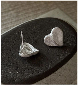 Macro detail of S925 sterling silver heart earrings with brushed matte finish texture