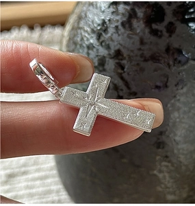 Macro shot of S925 silver cross pendant with sandblasted finish and star engraving