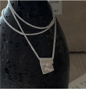 Detail of S925 silver necklace featuring a brushed texture pendant and pink crystal gem