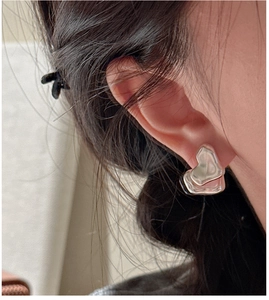 Primo piano di orecchini in argento S925 con design a cuore opaco indossati