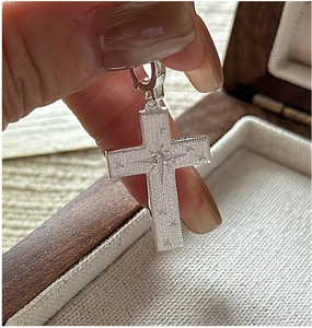 Detail of S925 silver cross pendant with frosted finish and starburst zircon inlay
