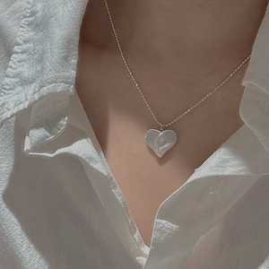 Collier cœur minimaliste en argent S925 avec texture lave porté par un mannequin chic