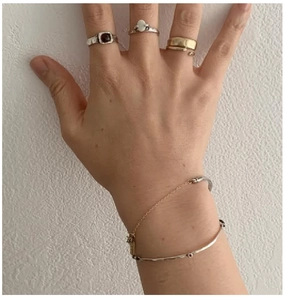Detail of mixed silver and gold chain bracelet with vintage gemstone rings on hand