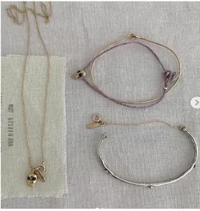Flat lay of vintage silver and gold bangles with skull pendant necklace and purple cord bracelet