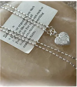 Close-up of S925 silver heart necklace with intricate filigree details and textured edges