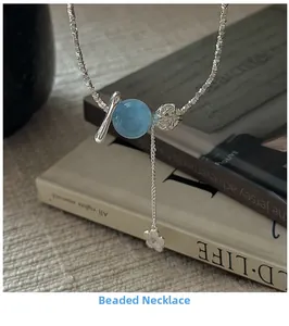 Détail d'un collier en argent perlé avec pierre bleue et pendentif fleur sur livres
