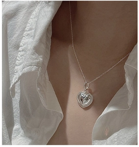 Détail d'un pendentif cœur en argent avec bordure perlée sur col de chemise