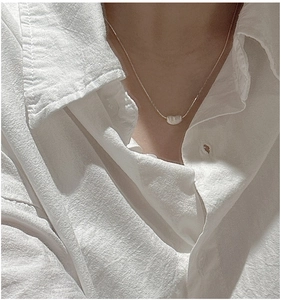 Gros plan du pendentif grain en argent S925 sur une chaîne fine de collier minimaliste