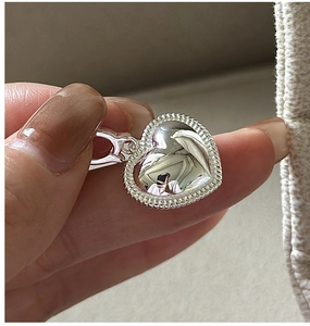 Gros plan d'un pendentif cœur en argent avec bordure milgrain et finition polie