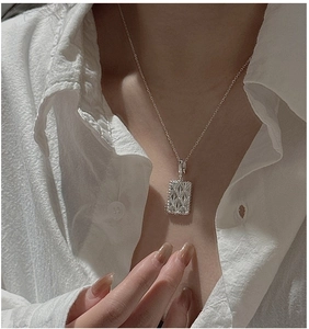 Detail of S925 silver rhombic pendant necklace on model with white cotton shirt