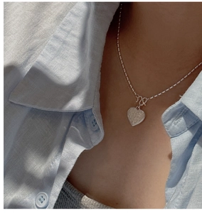 Macro detail of S925 sterling silver heart necklace with vintage texture on a bead chain
