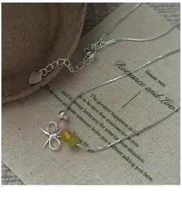 Macro shot of S925 silver bow pendant with colorful beads and sleek snake chain necklace