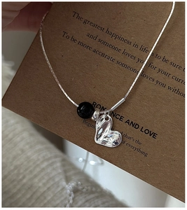 Detailed macro view of S925 silver heart necklace with black agate bead on card