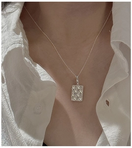Close-up of S925 sterling silver rhombic pendant on a necklace worn by a model