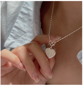 Detail of S925 silver heart pendant with vintage texture and unique cylinder chain link