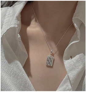 Close-up of S925 silver necklace with a diamond-patterned rectangular pendant on model