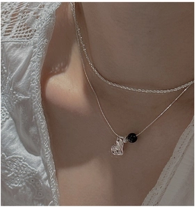 Close-up of double-layered S925 silver necklace with black bead and heart pendant